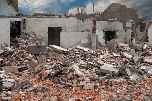 Demolishing site with ruined house and heap with bricks and other debris.