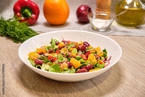 Vegetable salad with beans and orange on a white plate