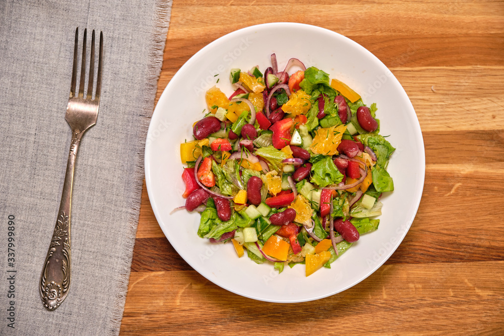 Vegetable salad with beans and orange on a white plate Vegetable salad with beans and orange on a white plate