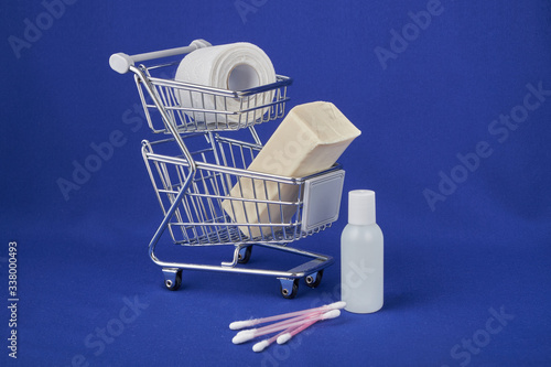 hygiene against viruses and bacteria concept, a bottle of hand sanitizer, toilet paper and soap inside a shopping basket symbol of highly sought-after products in times of self-isolation and quarantin photo