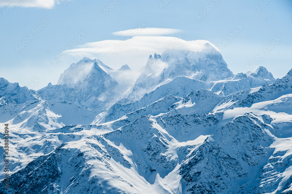 Obraz premium Mount Ushba in Caucasus mountains with snowstorm clouds on the ridge. Alpine winter view