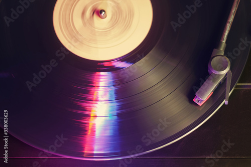 Record player with a spinning black vinyl record reflecting color lights