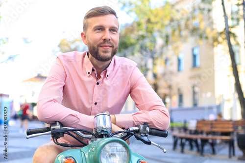 Handsome man posing on a scooter in a vacation context. Street fashion and style.