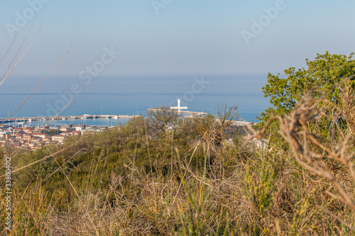 Christian crucifix on the hills over San Benedetto del Tronto  Marche   Italy. Pier in background with blue Adriatic sea