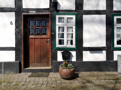 Schöne alte Haustür aus Holz und weißes Sprossenfenster eines Fachwerkhaus am Bartholdskrug bei Sonnenschein in Lipperreihe bei Oerlinghausen und Bielefeld im Teutoburger Wald in Ostwestfalen-Lippe photo