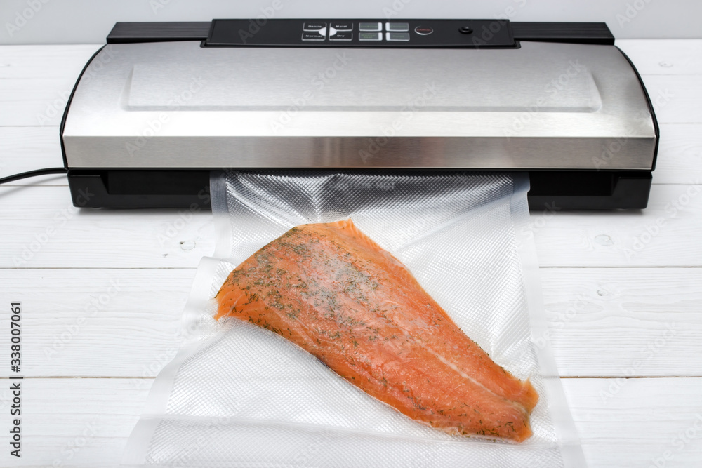 Vacuum food sealer with sealed and seasoned salmon fillet on white