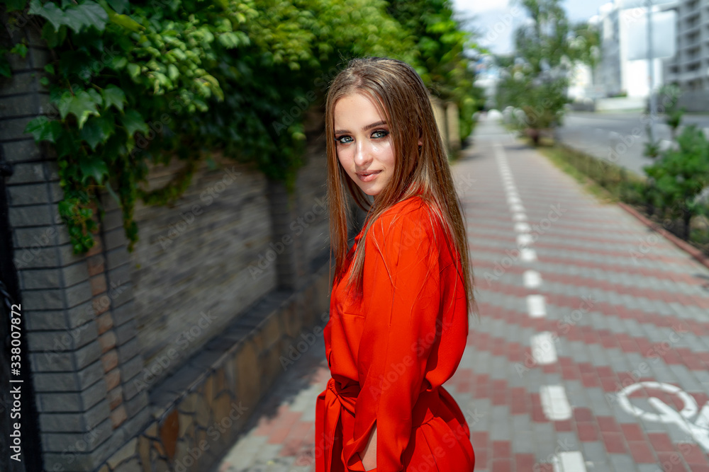 Fototapeta premium Beauty portrait of a young beautiful girl with long straight hair. Magnificent hair. Color portrait. Red dress.