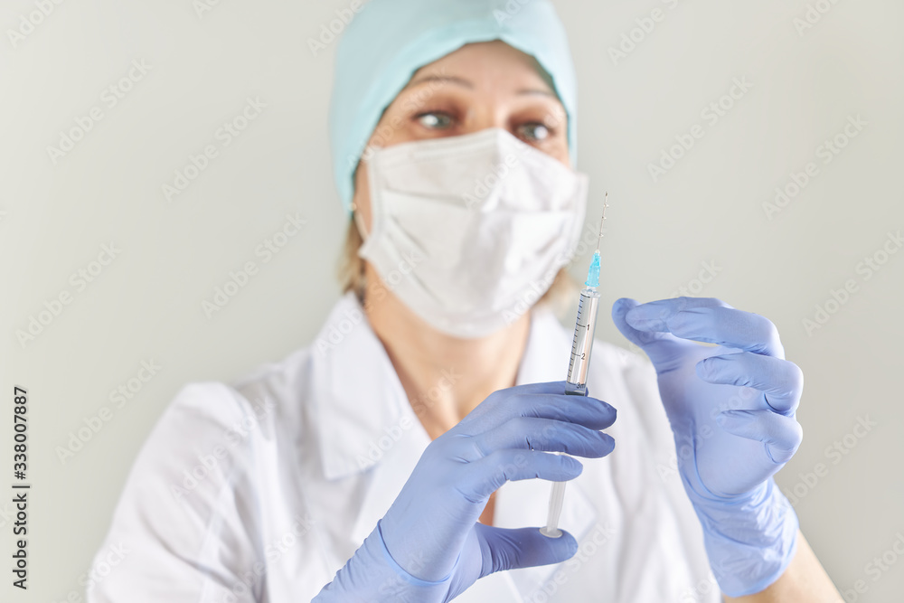 Doctor in the mask holds a syringe with a vaccine against the virus Doctor in the mask holds a syringe with a vaccine against the virus
