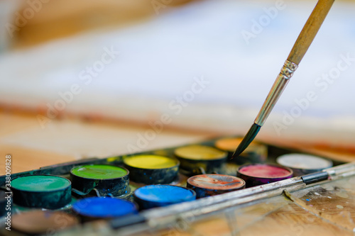 Watercolor palette and brush that are being used for painting at home.