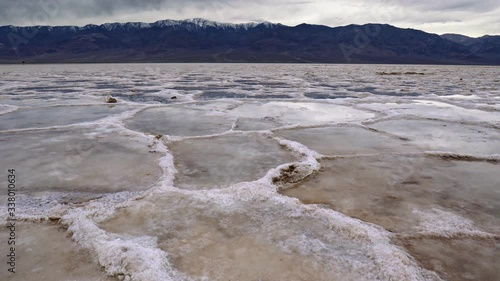 Death Valley National Park, California, USA. Lifting above salt masses on the coast of Badwater Basin. Panamint Range of mountains in the backgound. 4K, steadicam