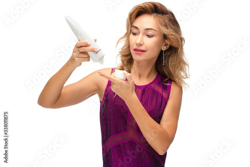 Studio stock photo of a gorgeous young adult woman in her 30s dropping lifting cream from the bottle onto her finger. Testing new anti-age product. Beauty and skincare concept. Isolate on white.