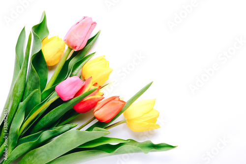 Beautiful tulips in bouquet lying on white background, top view