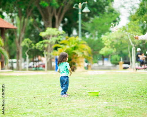 Lovely active little asian girl playing with soap bubble outdoor in the park