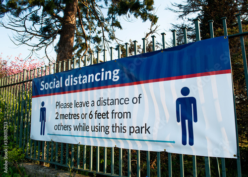 Large banner attached to railings, warning the general public to keep to the social distancing rules whilst using the public parks, in the London Borough of Bexley. photo