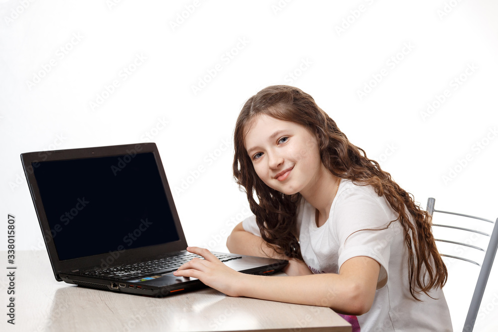 Cute schoolgirl sitting at a laptop on a white background Cute schoolgirl sitting at a laptop on a white background