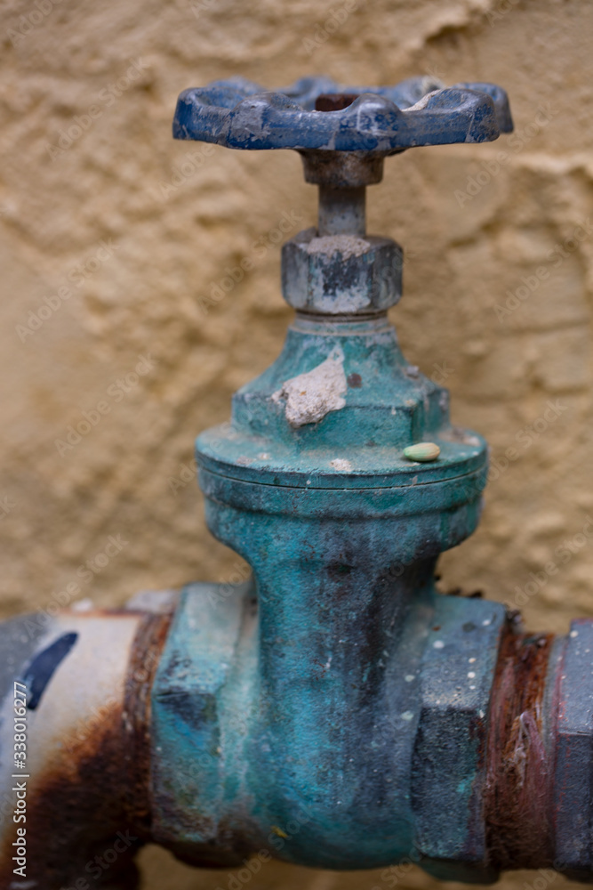 Close-up of the old rusty grunge steel pipe valve for water supply that stays at the outside of residence building.
Close-up of the old rusty grunge steel pipe valve for water supply that stays at the outside of residence building.