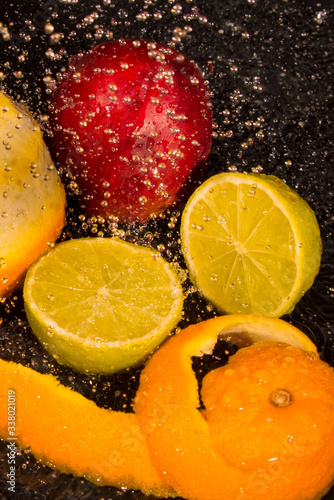 Fototapeta Naklejka Na Ścianę i Meble -  orange, lime, niktorin, drops of water on a black background