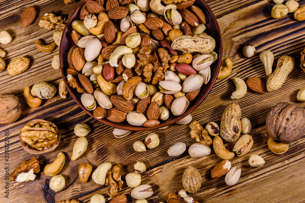 Various nuts (almond, cashew, hazelnut, pistachio, walnut) in ceramic plate on a wooden table. Vegetarian meal. Healthy eating concept. Top view Various nuts (almond, cashew, hazelnut, pistachio, walnut) in ceramic plate on a wooden table. Vegetarian meal. Healthy eating concept. Top view