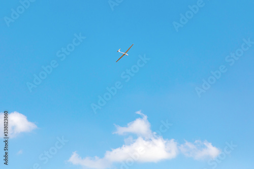 A sports glider in blue sky. A blue sky background with a small airplane to depict freedom, flight, endless possibilities
