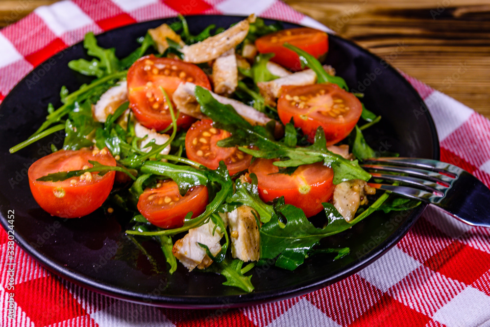Roasted chicken breasts and salad with arugula and cherry tomatoes in a black plate Roasted chicken breasts and salad with arugula and cherry tomatoes in a black plate