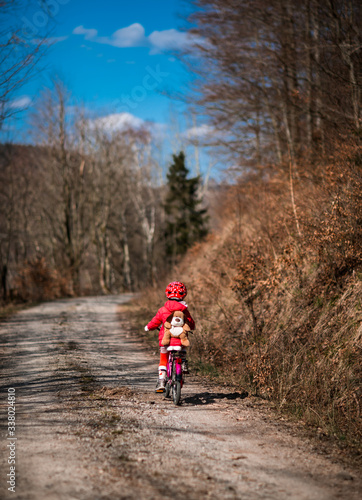 Five year old girl rides a pink bike in a forest in the mountains of German Harz