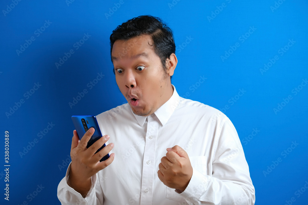Asian male office worker looks confident while accessing his smart phone Asian male office worker looks confident while accessing his smart phone