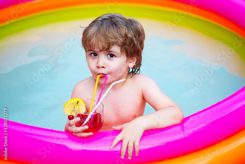 Cocktail in the pool. The child has a rest in the home inflatable pool with a fruit drink. Summer vacation. © Tverdokhlib