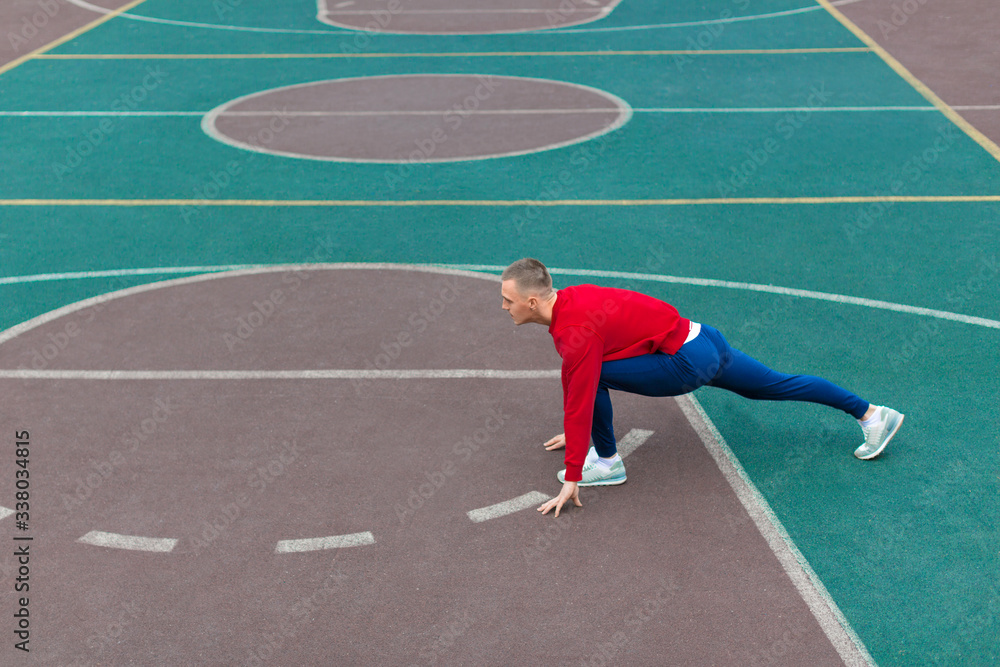 Photo of a man man flexes his leg muscles on the sports ground before running.