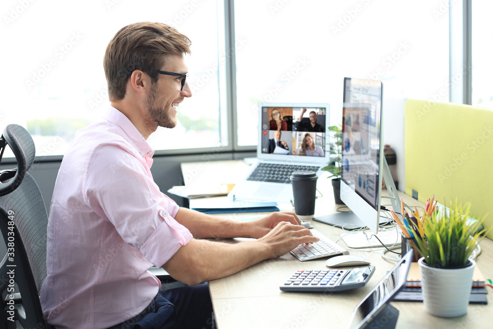 Young businessman working on computer, doing video conference with collegues on laptop. Distance work. Coronavirus. Young businessman working on computer, doing video conference with collegues on laptop. Distance work. Coronavirus.