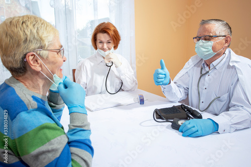 Fototapeta Naklejka Na Ścianę i Meble -  Doctors and an elderly patient are happy to defeat the coronavirus, smiling, removing medical masks.