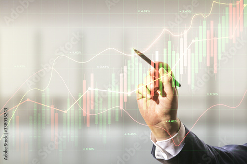 Double exposure of man hand with pen working with abstract creative financial chart hologram on blurred office background, research and strategy concept