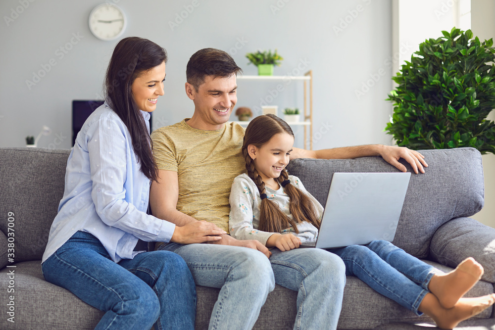 Happy family chatting online using laptop while sitting with baby on sofa at home. Happy family chatting online using laptop while sitting with baby on sofa at home.