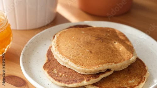 Putting freshly baked pancake on plate. Traditional american breakfast food, large buttermilk pancakes on a wooden table closeup view