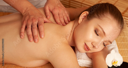 Beautiful young woman having a massage treatment in spa salon - wellness
