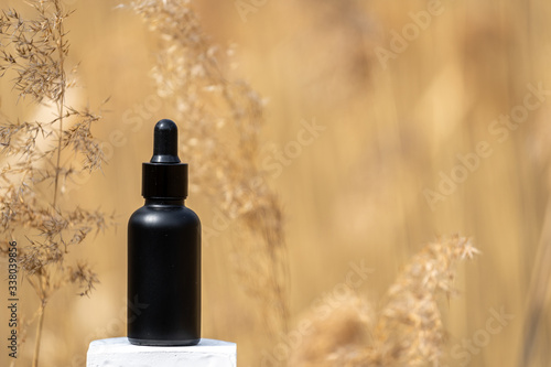 Serum oil in bottle with pipette against healing dry plants