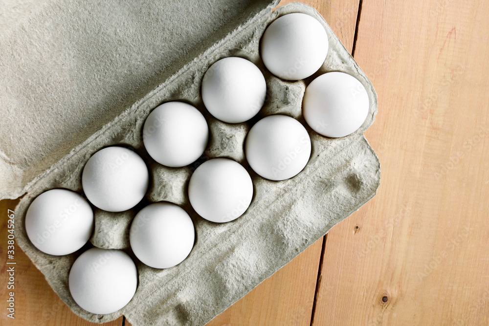 Cardboard or paper box of chicken white eggs on a wooden table, top view. Diet and agricultural food. Copy space Cardboard or paper box of chicken white eggs on a wooden table, top view. Diet and agricultural food. Copy space