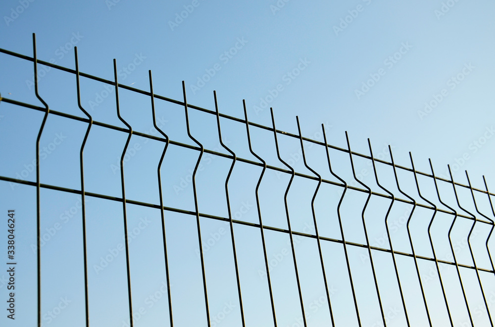 Background. A metal fence against a blue sky. Background. A metal fence against a blue sky.