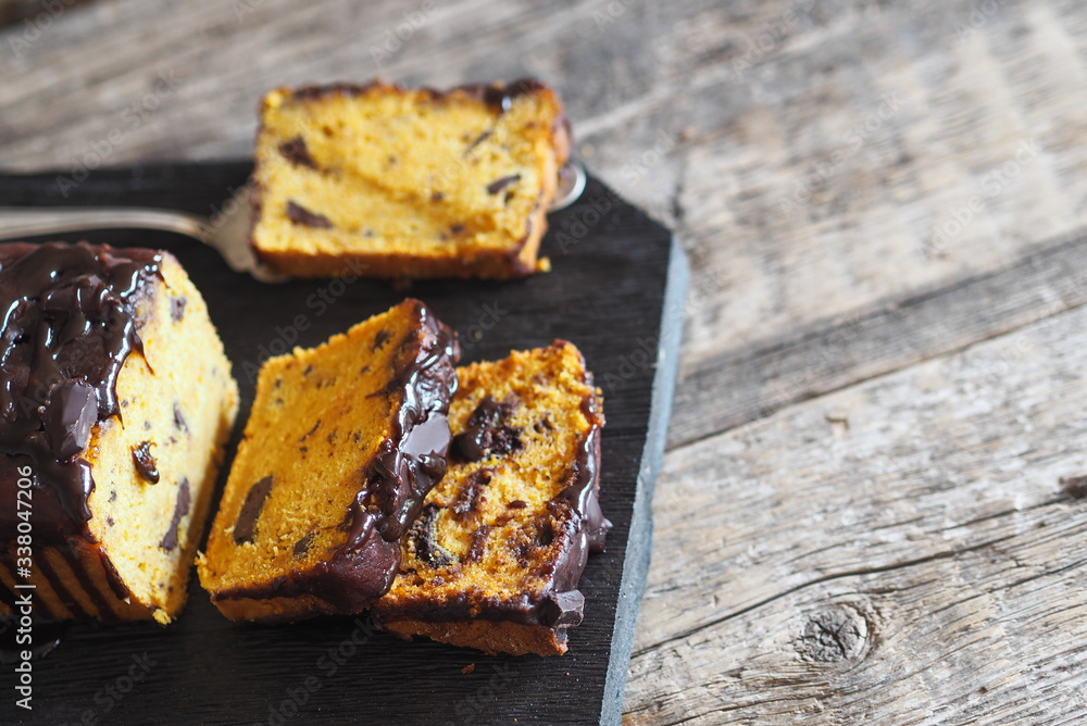 Festive chocolate soft pumpkin muffin, poured with chocolate icing, on a wooden ancient background. Festive chocolate soft pumpkin muffin, poured with chocolate icing, on a wooden ancient background.
