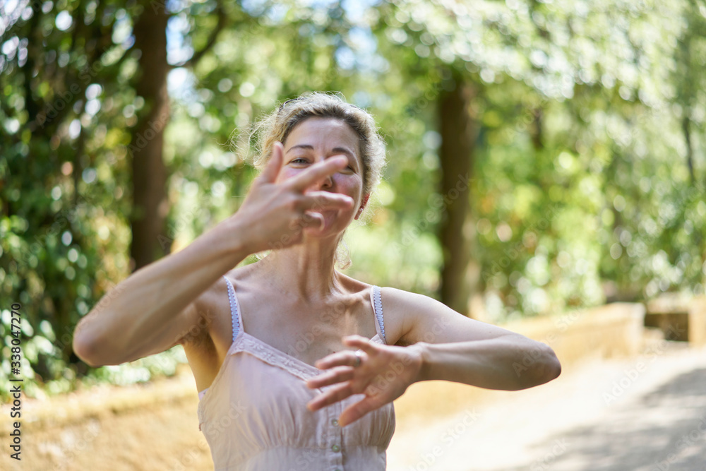 Woman doing chi gong exercises with her arms in a beautiful green park in summer Woman doing chi gong exercises with her arms in a beautiful green park in summer