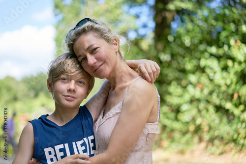 Loving mother and son embracing each other happily smiling on a summer day in a park