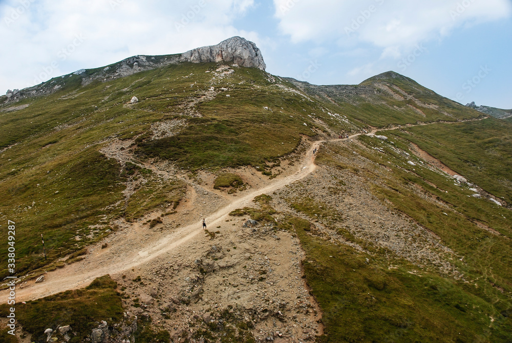 Hikers on a mountain path on a very hot summer day in the Romanian Carpathian Mountains.
