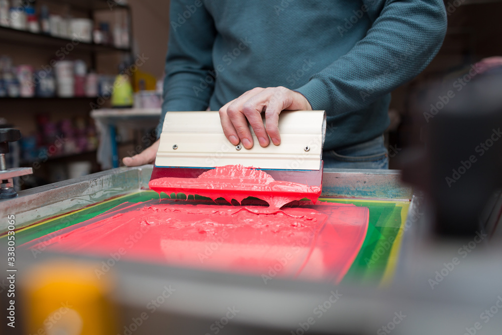 Silk screen printing. Serigraphy. Color paints and fabric. Plastisol paint and squeegee.