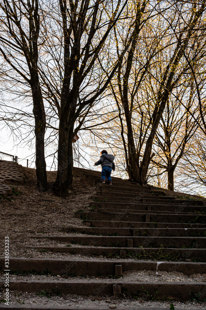 Obraz premium Child climbing on a stair on an autumn day with trees in the background