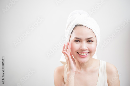 A woman is applying cream on her face