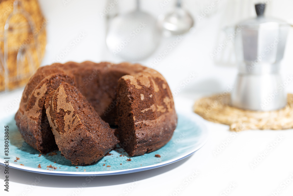 Chocolate cake with thread shape on white background with defocused kitchen objects background