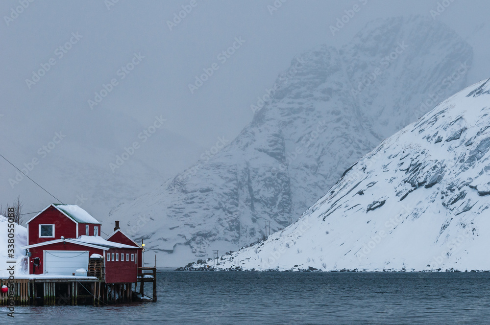 Waterfront buildings in front of snow covered mountains. Lofotern Islands, Norway.