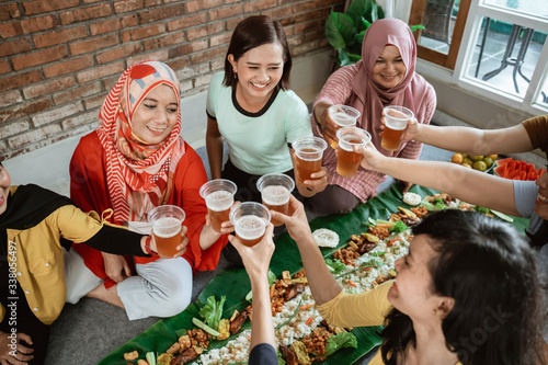 tea time with friend during lunch. muslim asian woman with friends together. toast their glass photo