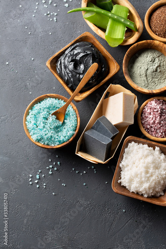 Fototapeta Naklejka Na Ścianę i Meble -  Spa. Natural cosmetics for the body and face. Blue sea salt with seaweed, soaps of herbs and dead sea mud, ground coffee scrub, aloe vera, clay for face mask on a dark table. Top view. Copy space.