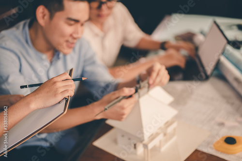 Male architect hands measuring and making model house with them team on the desk at sunset. Engineer, Engineering, Architecture, Design, Planning, Occupation concept..