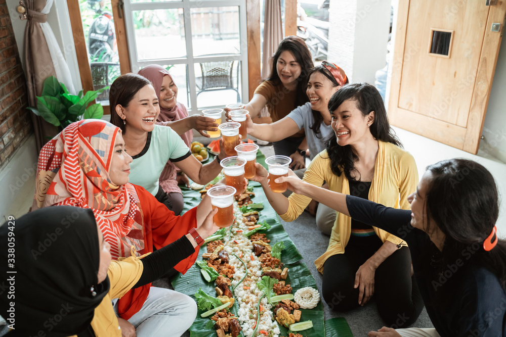 Obraz premium tea time with friend during lunch. muslim asian woman with friends together. toast their glass